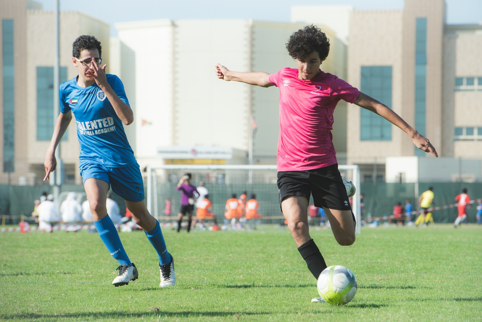 man in red shirt and black shorts playing soccer during daytime