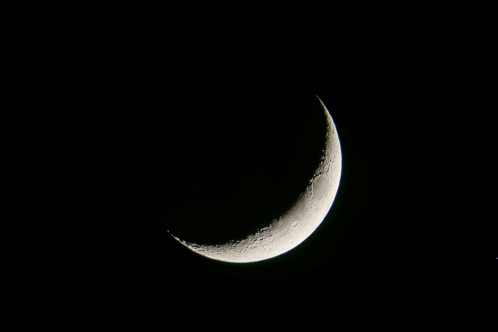 a half moon is seen in the dark sky